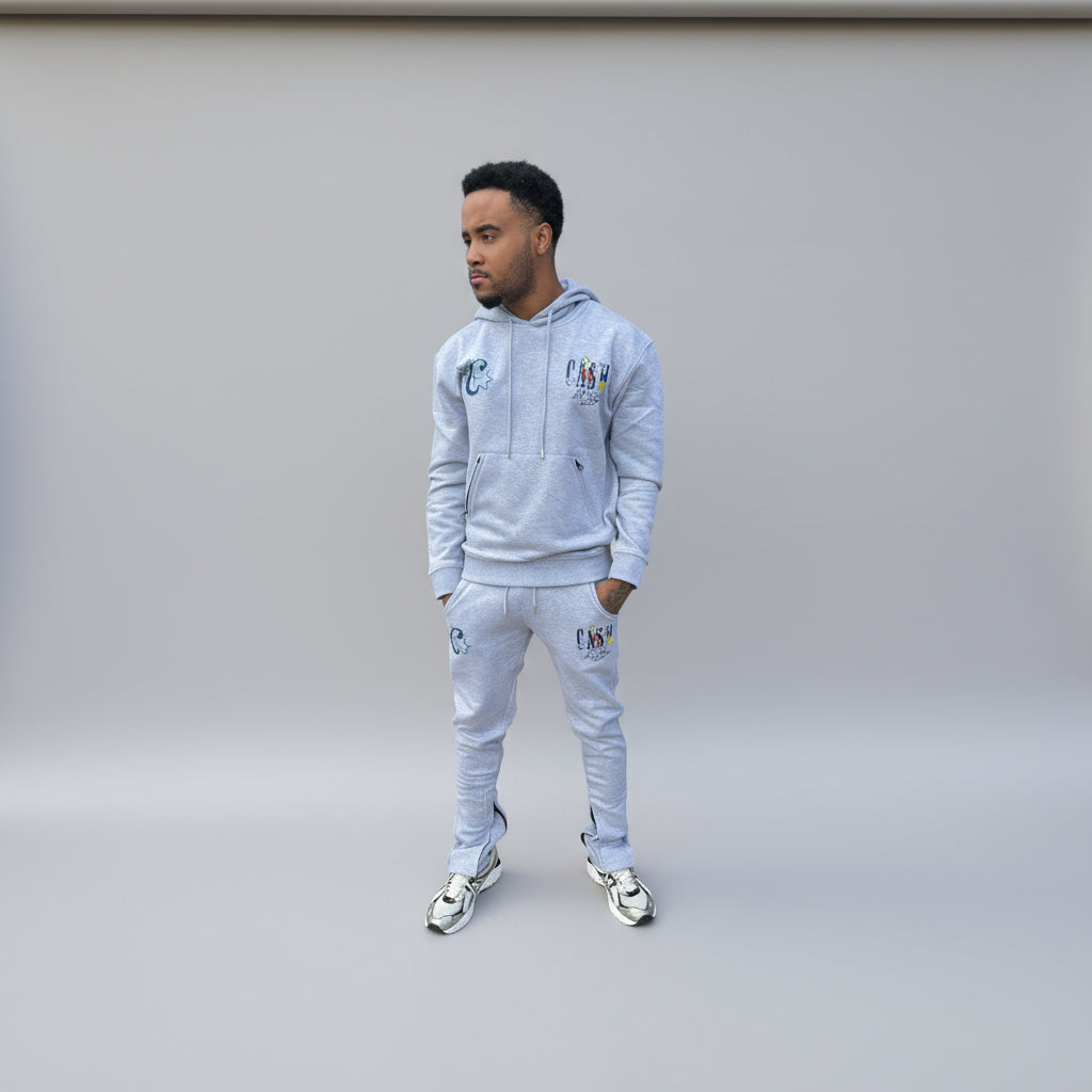 Man wearing a light gray tracksuit with brand logos on a white background